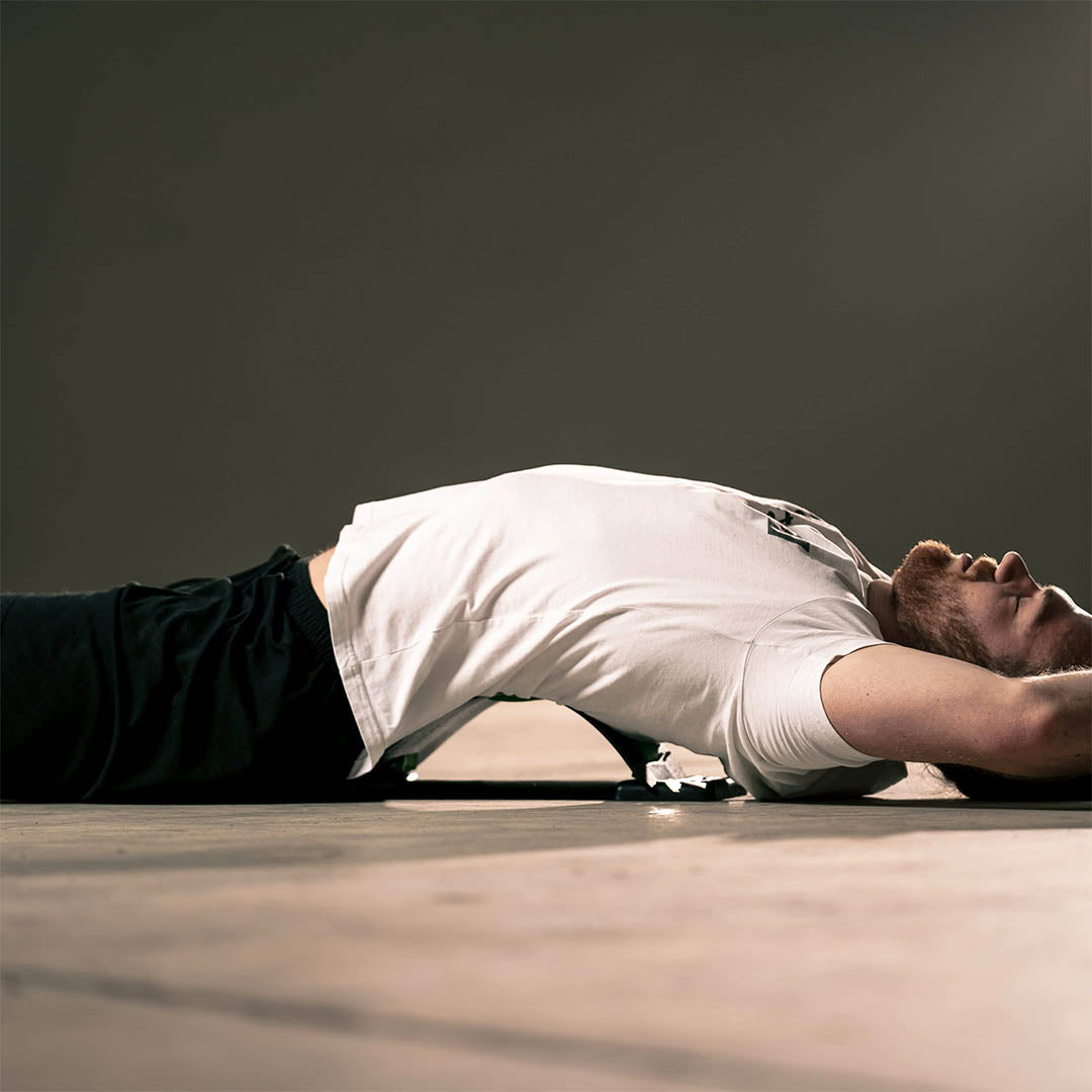 mand i hvid stretchfit tshirt lægger sig på rygstraekker backflex